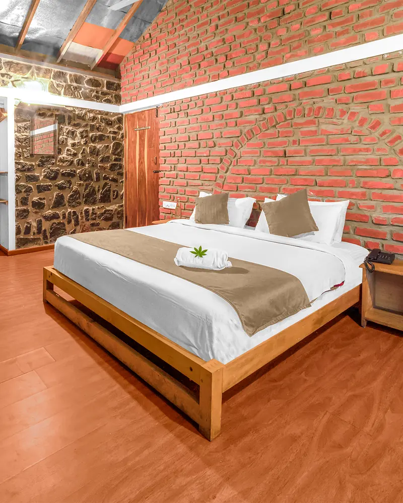 A guest room with exposed brick and stone walls and a king bed