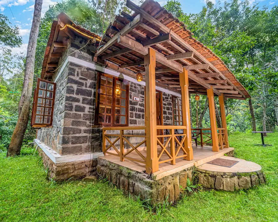 A stone cottage with a timber veranda, standing among the trees