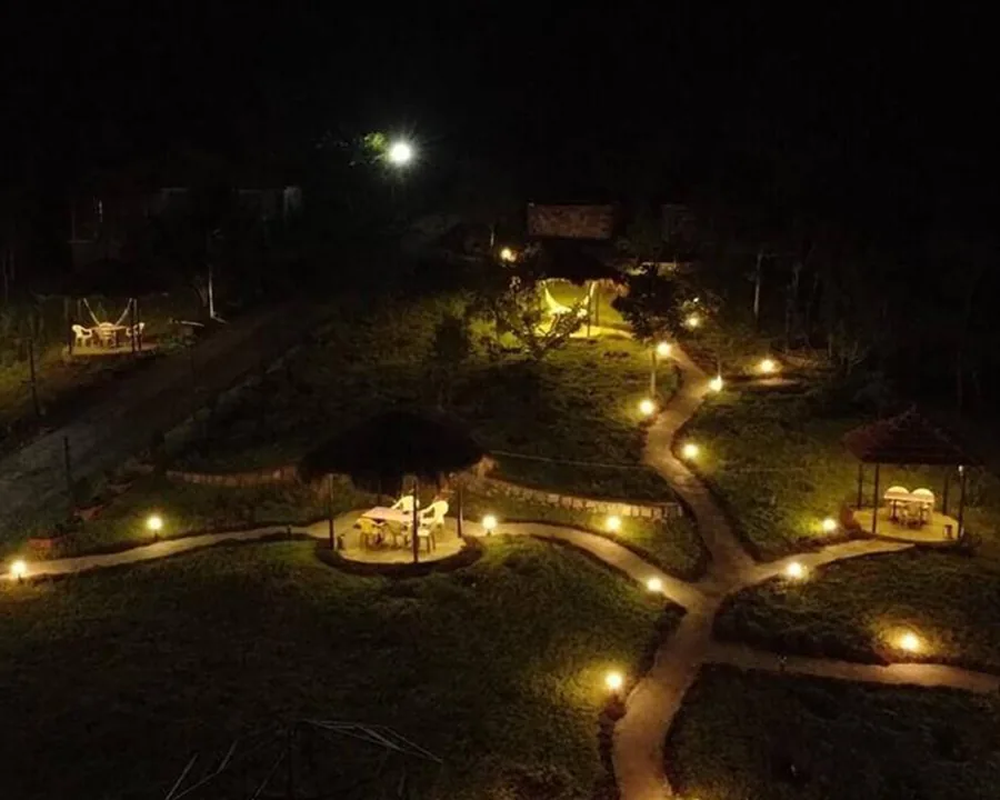 The property after dark, lit paths running between the lawns, gazebos and cottages