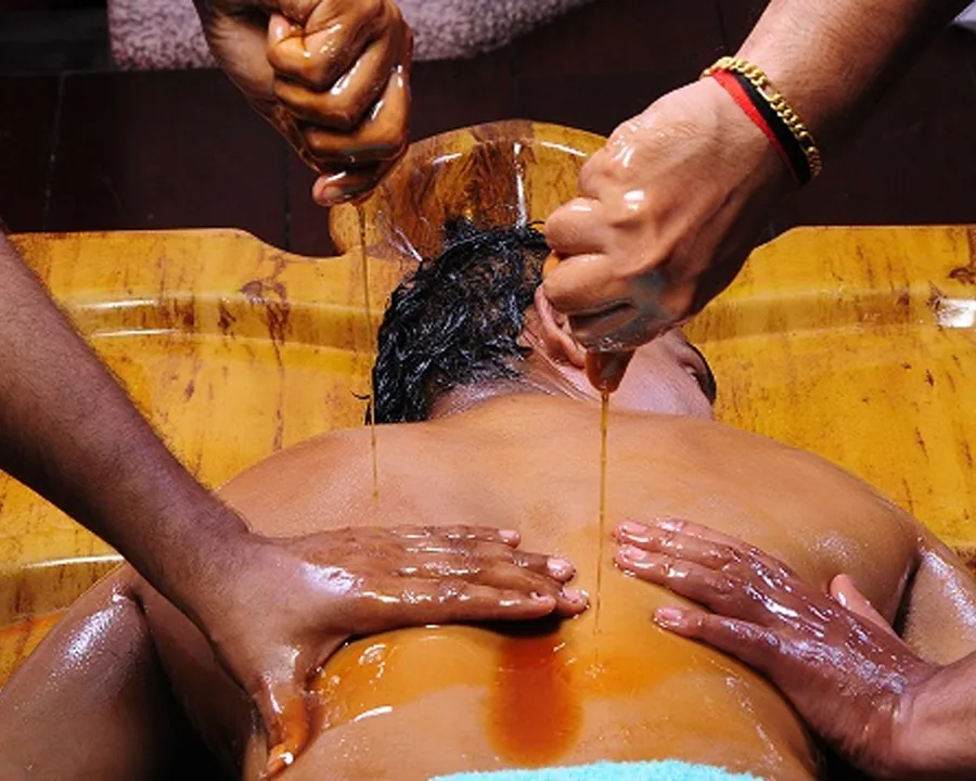 Warm oil squeezed from cloths over the body while two therapists work it in